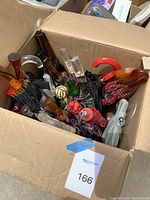 Cardboard box containing multiple umbrellas with assorted handles visible.