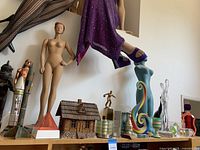 Top shelf view showing warrior, copper figure, two rockets, mannequin, red pyramid and cabin