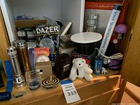 Overall assortment of items including flashlights, toys, keychains, a stuffed bear, Etch A Sketch, and Monopod selfie stick on wooden surface.