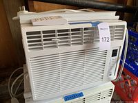 Front view of white GE window air conditioner with vented grill and remote control on top, showing size tape with dimensions 13 x 16 x 13 inches.