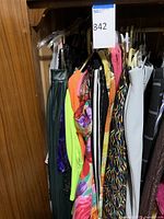 Closet view of assorted ladies dresses and skirts on hangers showing various colors and fabrics.