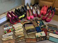 Wide view showing 12 pairs of women's high heel shoes in various colors including pink, black, neon yellow and more, arranged behind about 26 eyeglass cases in assorted patterns and colors on the floor.