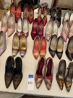 Wide view of 20 pairs of women's high heels in various styles and colors arranged on a table
