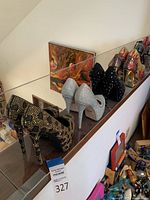 Side and angled view of the front five pairs of high heel shoes arranged on a wooden ledge, showing a variety of colors and embellishments.