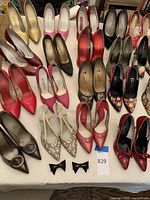 Top view showing 18 pairs of ladies high heel and stiletto shoes in various colors and styles laid out on a flat surface.