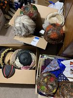 Two cardboard boxes containing six vintage hats and a basket of fabric scraps