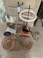Overall lot showing white ceramic lamp with clock, modern decorative lamp, pink lace metal lamp shades, lamp base with fluorescent ring light, and small clocks.