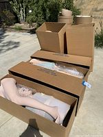 Four large cardboard boxes containing parts of female mannequins, including legs and heads wrapped in bubble wrap.