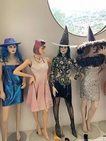 All four mannequins shown standing side by side against wall under round window