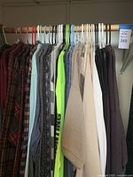 Closet rod showing flannel, sweaters, and light-colored shirts.