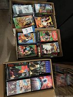 Three boxes of VHS tapes from above, assorted titles visible