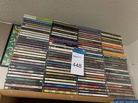 Photo showing a large stacked collection of mixed artist CDs in jewel cases arranged in columns