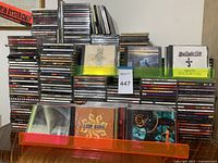 Large assortment of stacked CDs with visible titles including Blue Öyster Cult, Loop Guru, Roxy Music.