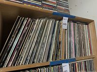 Wooden shelving unit filled with rows of vinyl LP records of varying spine widths and colors