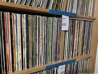 Two wood shelves filled with vinyl LP sleeves labelled 450 and 451