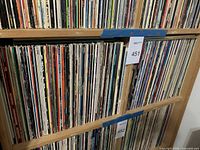 Two wooden shelves filled with vinyl record spines, top shelf labeled 451 and bottom shelf labeled 452