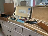 Multiple eyeglass and sunglasses cases displayed in open metal organizer and wooden hinged box