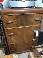 Front view of the vintage wooden dresser showing the four deep drawers and decorative brass handles.