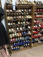 Wooden shoe rack filled with multiple pairs of women's shoes, showcasing the rack's size and shelf capacity.