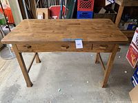 Front view of wooden mission style desk showing top surface, legs, and three drawers.