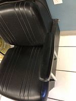 Close-up of black vinyl padded chair seat and armrest with stitch detail