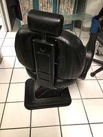 Rear view showing the adjustable headrest attachment and black vinyl upholstery with some visible seams.