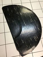 Large half circle black rubber floor mat with white streaks placed on tiled floor, shown from a top angle revealing texture and wear.