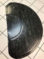 Top view of large black and white rubber floor mat on tiled floor showing marbled streak pattern and half circle shape.