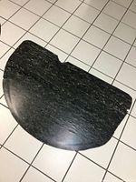 Large half circle black and white rubber floor mat on tiled floor, showing texture and wear.