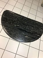 Top-down view of large half circle black and white rubber floor mat showing texture and shape.