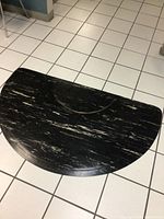 Full view of large half circle floor mat with marbled black and white rubber pattern, showing front surface and curved edges.