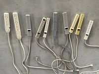 Top-down photo showing 10 power bars aligned side by side on a floor surface. White, beige and grey power bars are included with power cords and plugs visible.