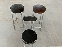 Top view of three retro vintage barstools with two round cushioned seats and one with backrest, showing seating surfaces and frame legs.