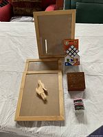 Photo of the full lot showing three wooden picture frames, ornamental carved wooden box, wooden hand-shaped wine stopper, bead wine glass markers, and boxed Rubik's Cube.