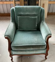 Front view of armchair showing velvet upholstery, tufted backrest, seat cushion and pillow