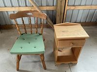 Full view of wooden chair with green cushion and pine side table with drawer.