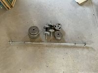 Full set showing the 5-foot bar, multiple weight plates, and two dumbbells arranged on floor.