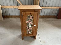 Photo of mini wooden credenza closed showing floral painted front door and white round knob