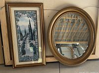Photo of oval mirror and framed print titled "Road to Tuscany" hung on a wall together.