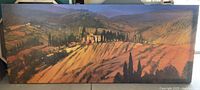 Framed poster depicting a landscape painting or print of Tuscany at sunset with an orange-brown color scheme, measuring approximately 62 inches wide and 26 inches tall.