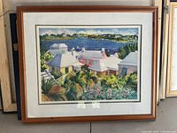 Framed print showing a colorful Bahamas scene with houses, palm trees, and water body.