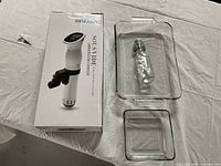 RioRand sous vide immersion cooker box, two glass pans, and glass bottle shown on table