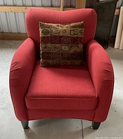 Front view of cranberry red upholstered accent chair with patterned pillow on seat.
