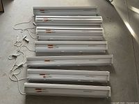 Seven white Hunter Douglas Pirouette window shades laid out on floor showing size and condition.