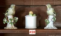 Front view of two German porcelain bird figurines with a small English porcelain jam pot between them.