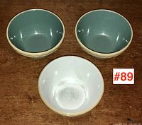 Three English stoneware bowls shown from above and one inverted revealing interior base and pattern, set on wooden surface with lot number #89 visible.