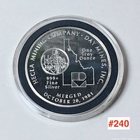 Front side of silver coin showing Hecla Mining Company logo, map outline, weight and fineness markings.