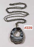Full view of agate slice pendant on silver chain laid flat showing the pendant's front and chain length.