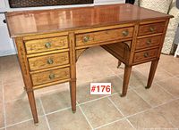 Front view showing seven drawers, kneehole arch, marquetry details and brass hardware