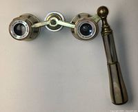 Top angled view of opera glasses illustrated full item appearance, showing mother of pearl handle and clear branding on eyepieces.